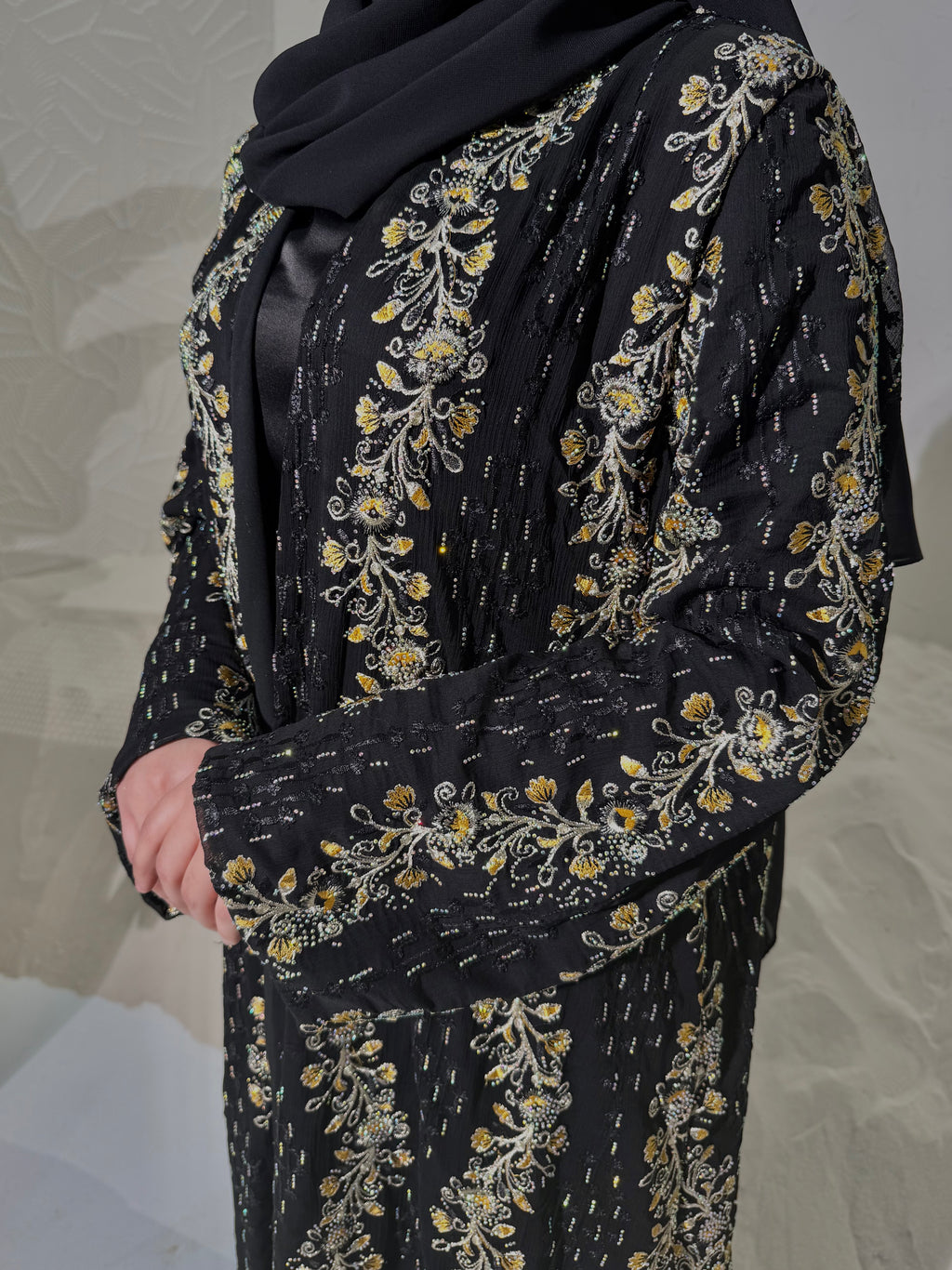 Black outfit with gold floral embroidery on a neutral background
