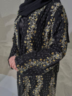 Black outfit with gold floral embroidery on a neutral background