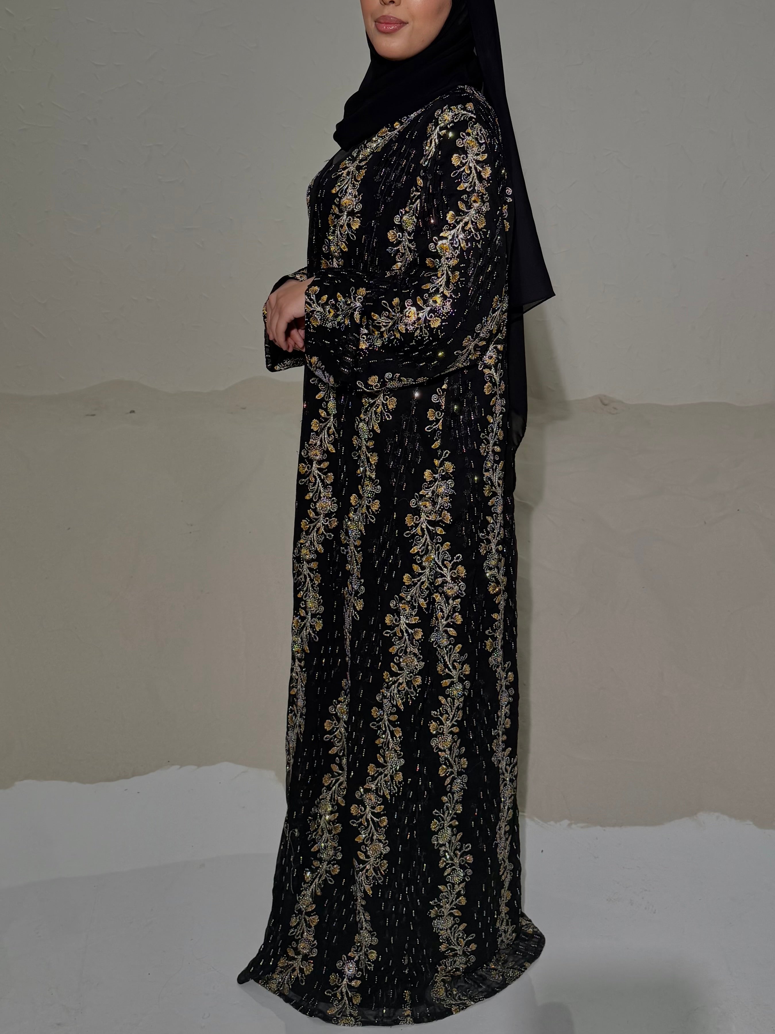 Black abaya with gold embroidery on a plain background
